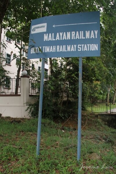 A old signboard pointing towards Bukit Timah Station from the main road.