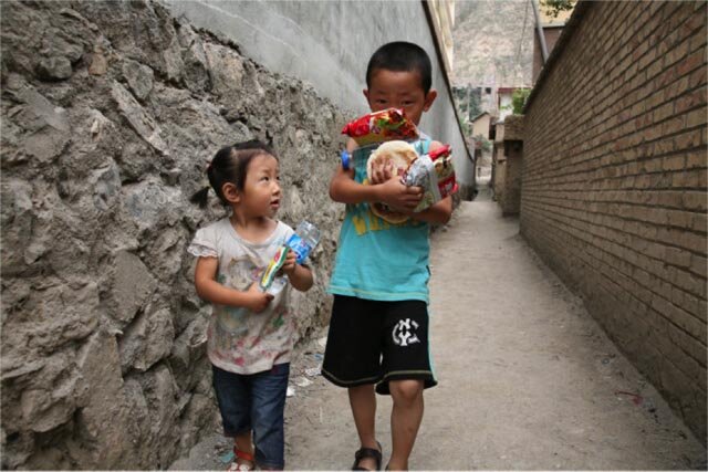 Children carrying food rations in devastated Zhouqu County